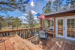 A wooden deck with a table and chairs, a glass door with a view, and an American flag.