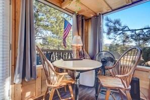 A wooden deck with a round table and two chairs, a lamp, and a fan.