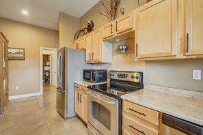 A kitchen with stainless steel appliances, wooden cabinets, and a countertop. - 3BD |Cowboy Quarters Retreat Experience (Larkspur)