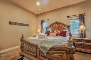 A bedroom with a large bed, bedside tables, a coat rack, and a window with curtains. - 3BD |Cowboy Quarters Retreat Experience (Larkspur)