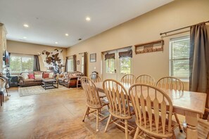 A spacious living area with a large dining table, multiple chairs, and a sofa.