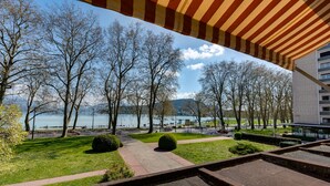 A park with pathways, trees, and a view of a lake and mountains. - Swan Lake - Design apartment facing Lake Annecy (Annecy)