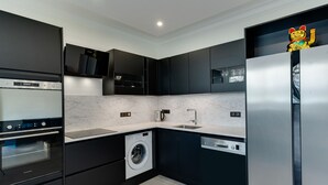 A modern kitchen with built-in appliances, a washing machine, and a sink. - Swan Lake - Design apartment facing Lake Annecy (Annecy)