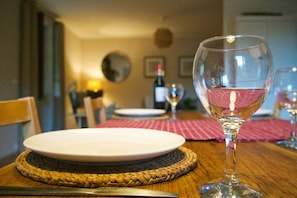 A dining table with a wine glass, plates, and cutlery. - Secluded Gite, private garden, large heated pool, tranquil setting (Cuzorn)