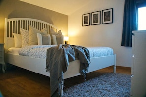 A bedroom with a bed, pillows, a blanket, a nightstand, a lamp, and three framed pictures on the wall. - Secluded Gite, private garden, large heated pool, tranquil setting (Cuzorn)