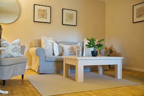 A living room with a grey sofa, a white coffee table, and a potted plant. - Secluded Gite, private garden, large heated pool, tranquil setting (Cuzorn)