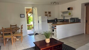 A compact living space with a dining area, kitchenette, and a small garden view.