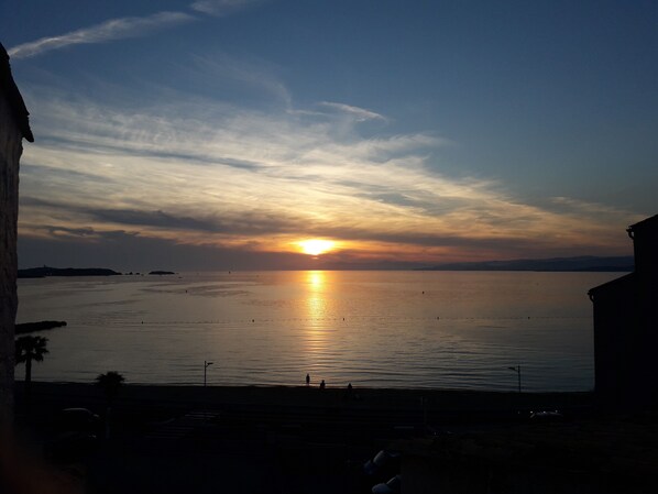 A sunset over a calm body of water with distant landforms. - Logement en Copropriété Avec Terrasse Face à la Plage (Six Fours les plages)