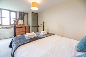 A bedroom with a bed, a dresser, a mirror, and a window.