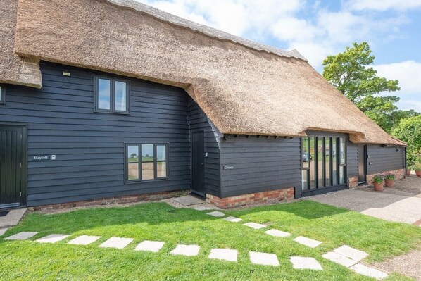 A building with a thatched roof and dark siding, labeled "Hayloft" and "Granary".