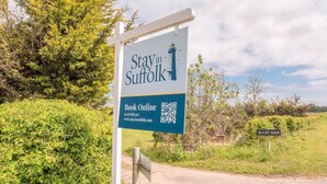 A sign for Stay in Suffolk with a QR code, a booking number, and a website URL. - Stables at Valley Farm Barns, Snape (Saxmundham)