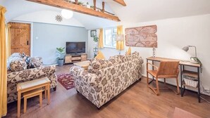 A cozy living room with a sofa, a wooden desk, and a television. - Suncatch Corner, Saxmundham (Saxmundham)