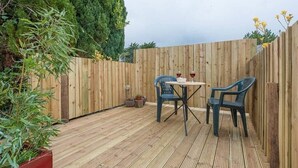 A wooden deck with a table and chairs, surrounded by a wooden fence and potted plants. - Suncatch Corner, Saxmundham (Saxmundham)