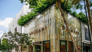 A BVLGARI store with a modern glass facade and palm trees in the foreground. - Modern Rustic 1Bdrm Condo W/Bay & Pool Views (Miami)