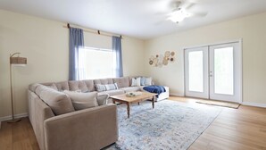 A living room with a beige sectional sofa, a wooden coffee table, and a patterned rug.
