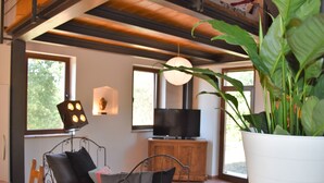 A cozy room with a bed, a TV, and a large potted plant.