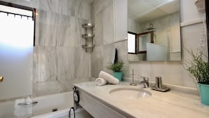 Un baño moderno con bañera, lavabo, espejo y ducha.