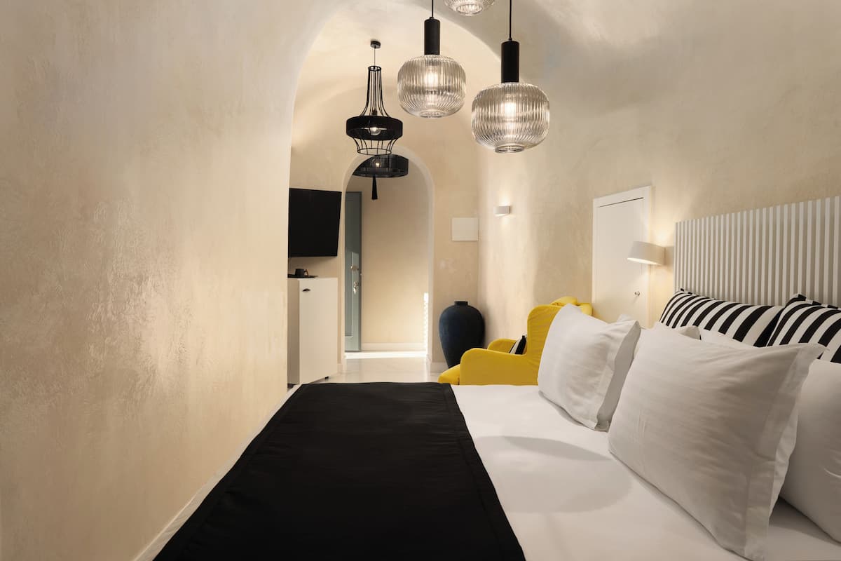 A bedroom with a bed, a TV, and a yellow chair.