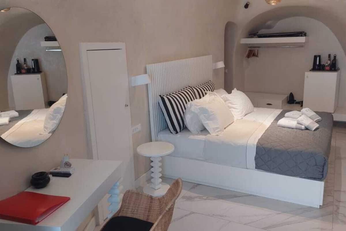 A bedroom with a bed, a bedside table, a chair, a mirror, and a wardrobe.