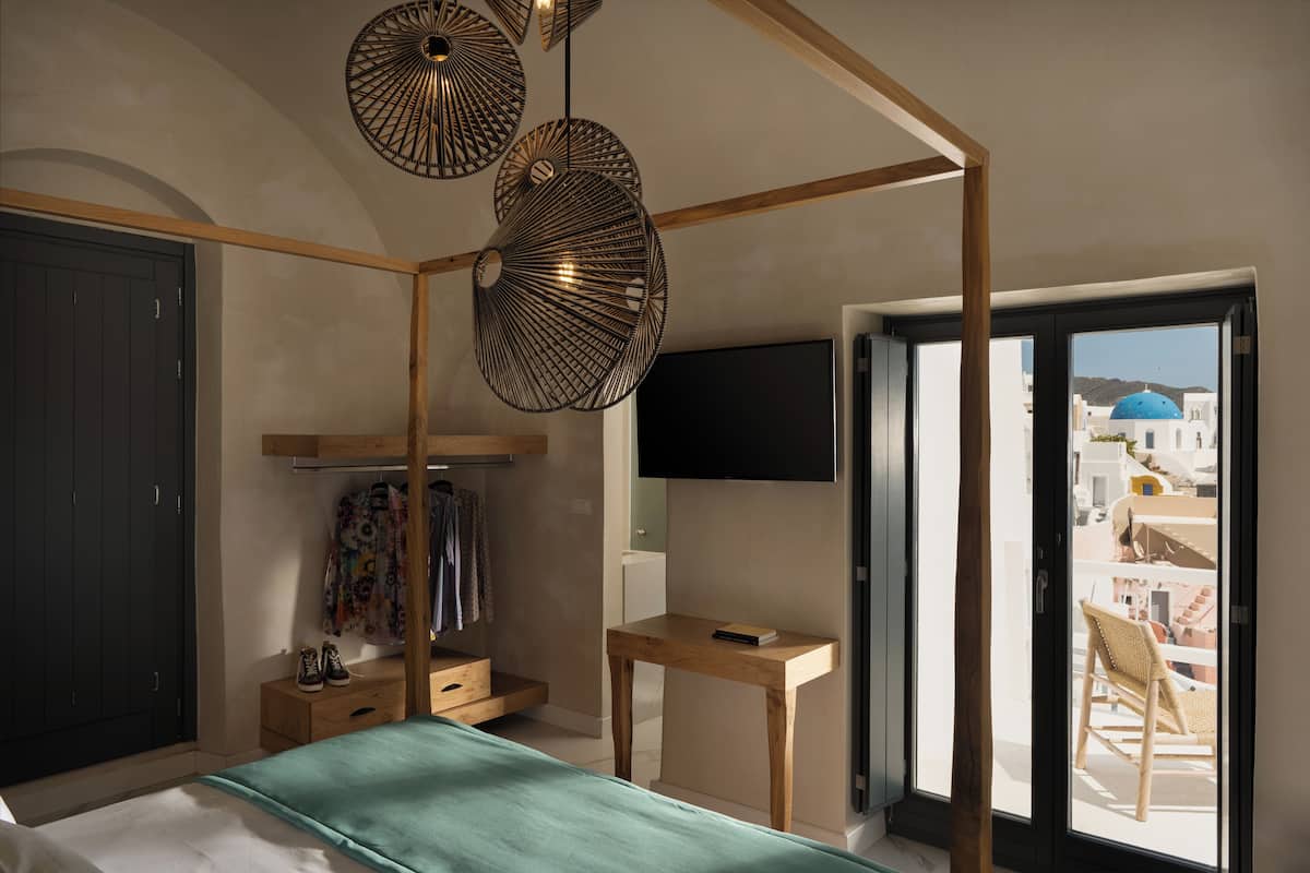 A bedroom with a bed, a wardrobe, a desk, a chair, and a TV.