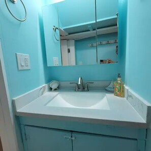 Een badkamer met een witte wastafel, een spiegel en een zeepdispenser.