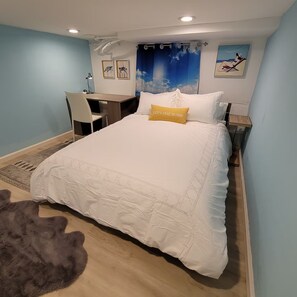 Une chambre à coucher avec un lit, un bureau, une chaise, un tapis et un tableau accroché au mur.