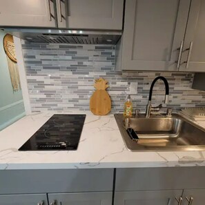Una cocina de diseño moderno, con un lavamanos de acero inoxidable, horno empotrado y salpicadero con un diseño de mosaico.