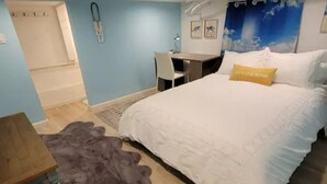 A bedroom with a bed, a desk, and a chair.