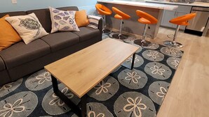 A living room with a sofa, a coffee table, and a patterned rug.