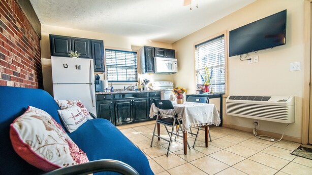 A compact kitchen with a refrigerator, microwave, stove, and a dining area with a table and chairs.
