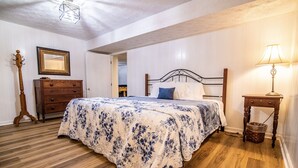 A bedroom with a bed, wooden dresser, and a nightstand with a lamp.