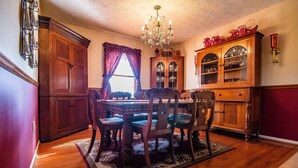 A dining room with a wooden table, chairs, a chandelier, and a cabinet with glass doors.