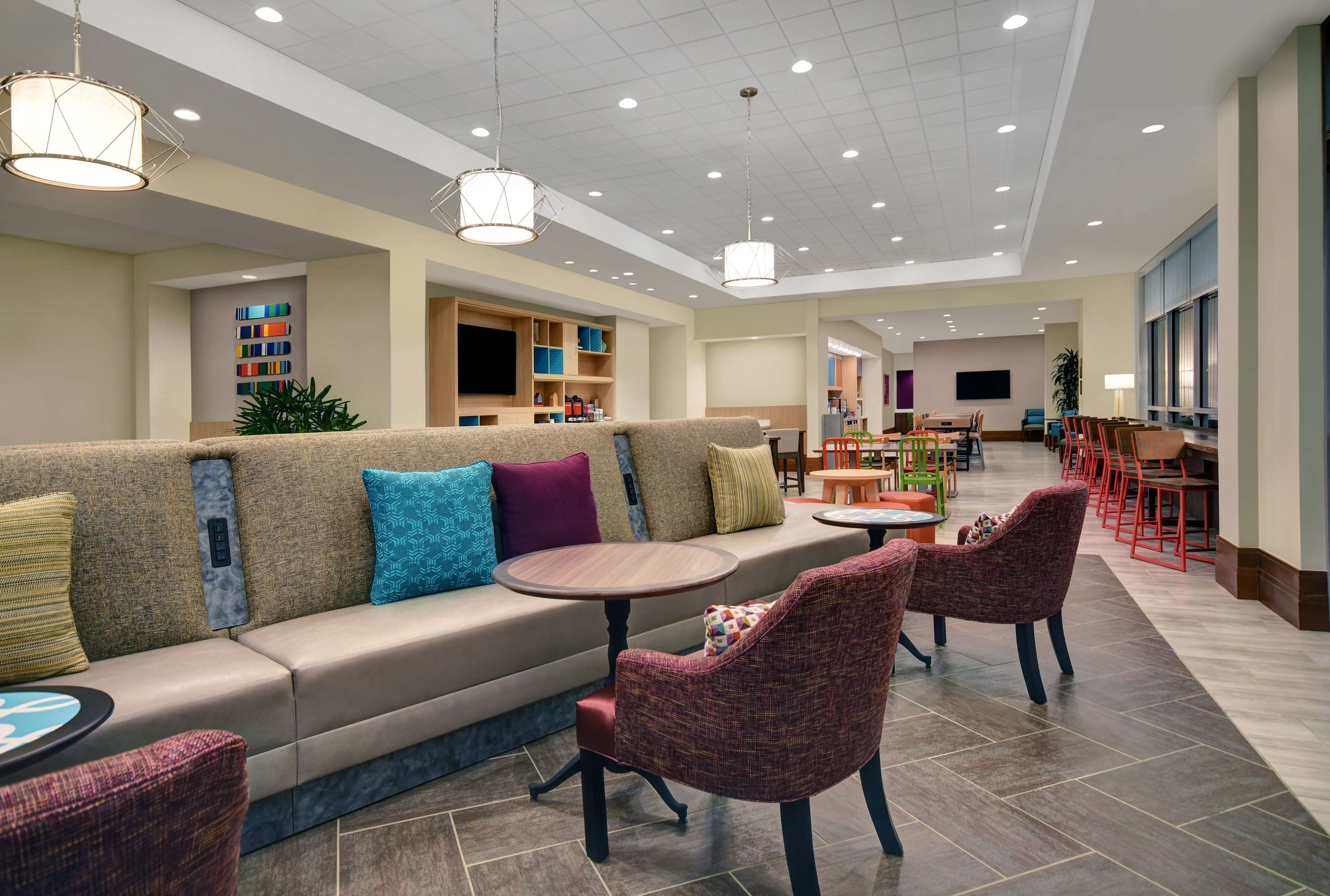 A modern lobby with a sofa, chairs, a round table, and a bookshelf.