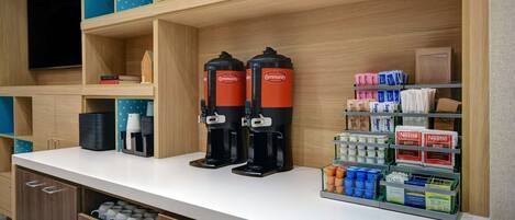 Un espace dédié au café, équipé de deux machines à café, d’un assortiment de capsules de café et d’un distributeur de boissons.