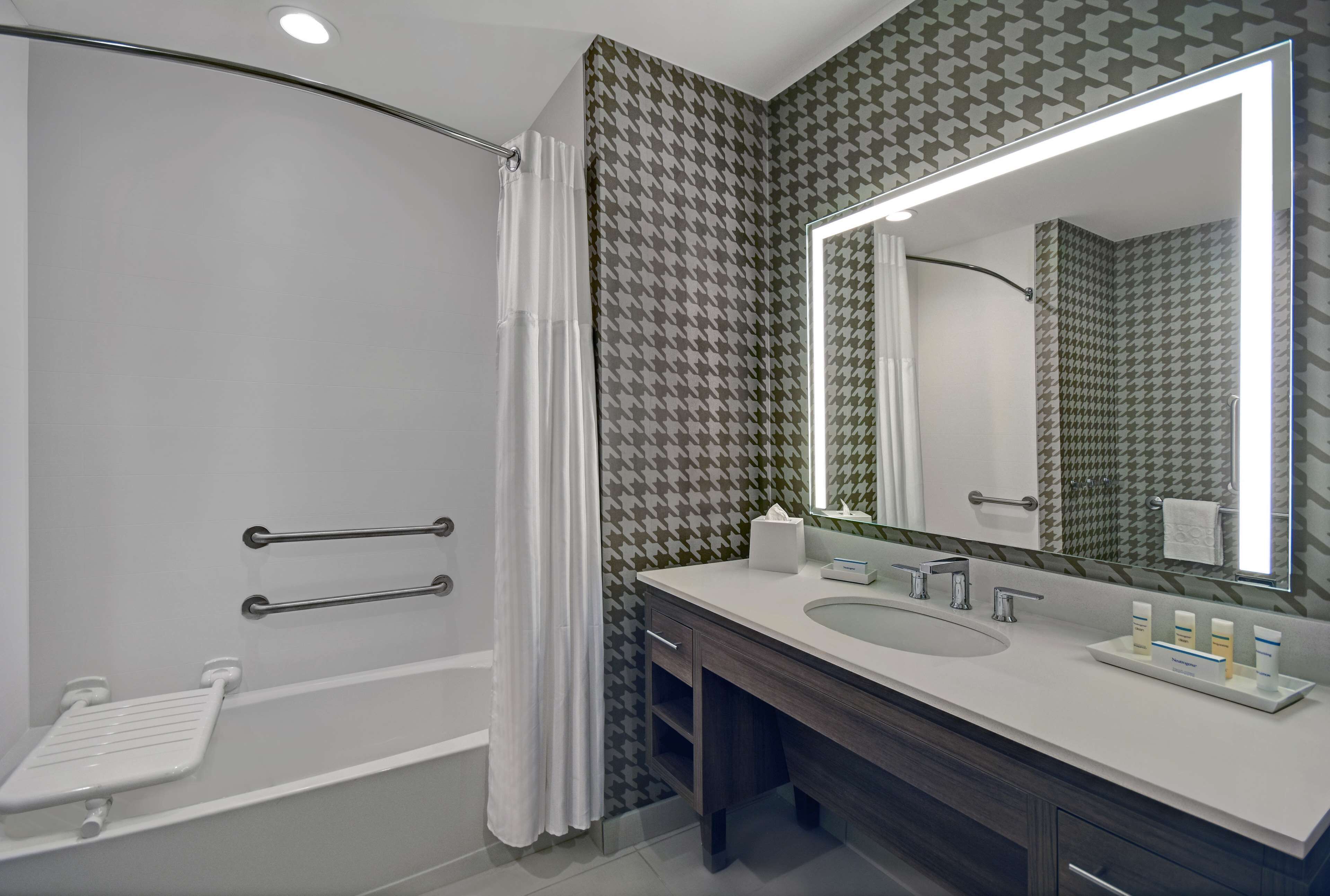Une salle de bain moderne équipée d’une douche, d’un meuble-lavabo avec un grand miroir et de toilettes.