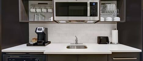A modern kitchen with a built-in microwave, coffee maker, and dishwasher.