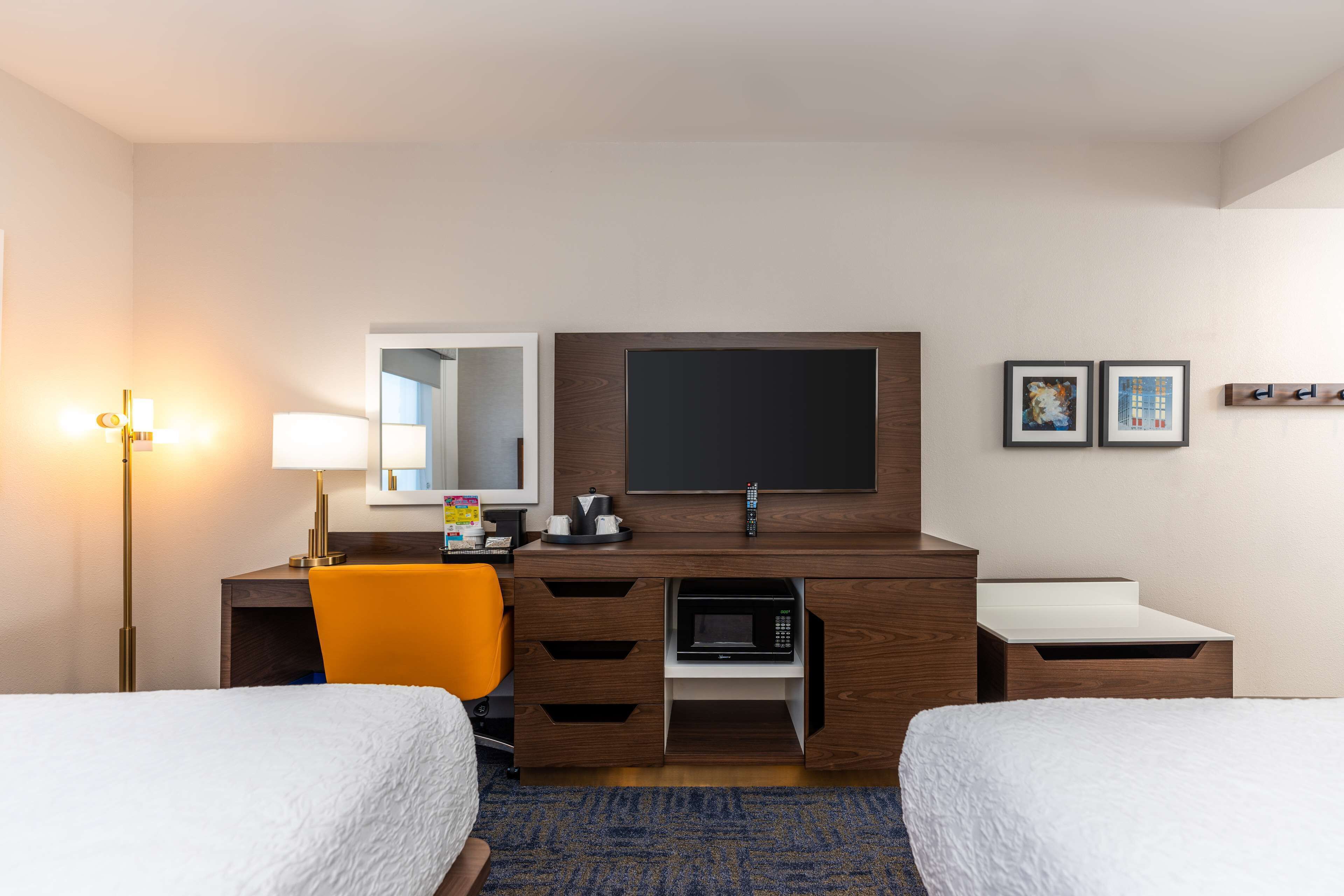 Une chambre d’hôtel avec deux lits, un bureau doté d’un téléviseur à écran plat, un four à micro-ondes et une lampe.