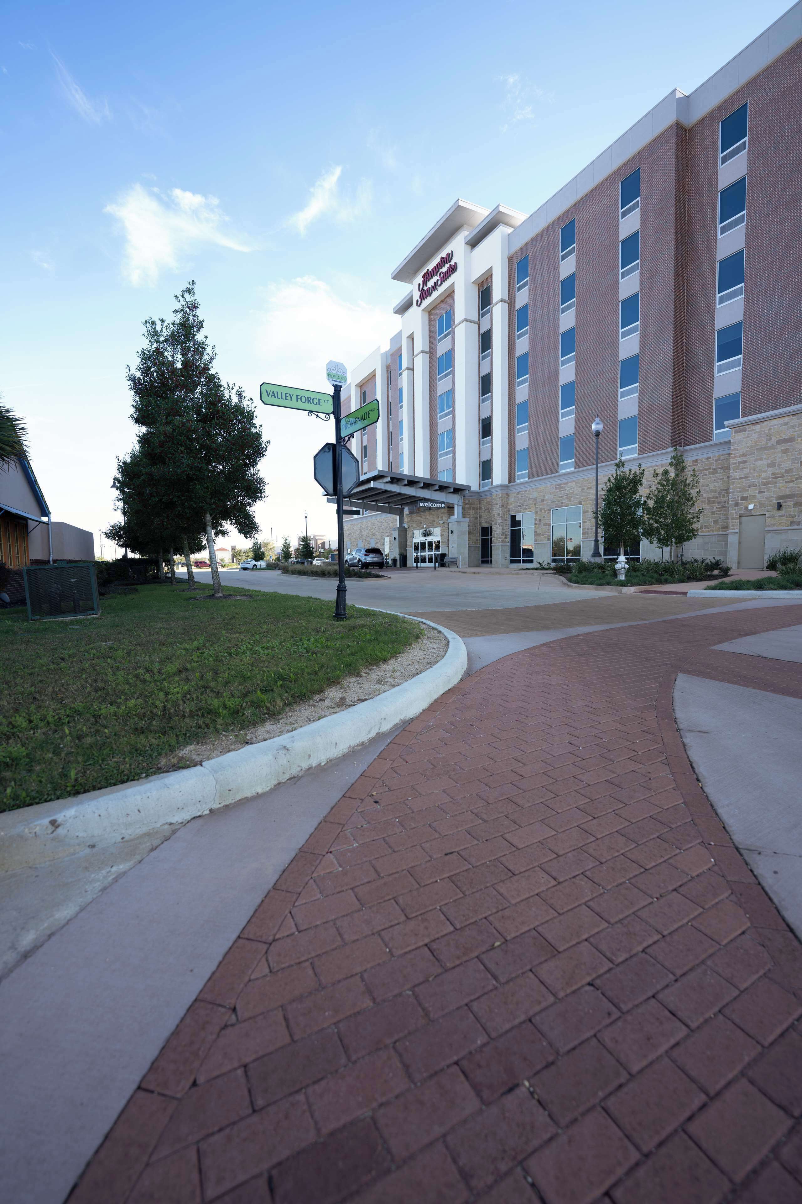 A hotel with a brick facade, a covered entrance, and a landscaped area with a pathway.