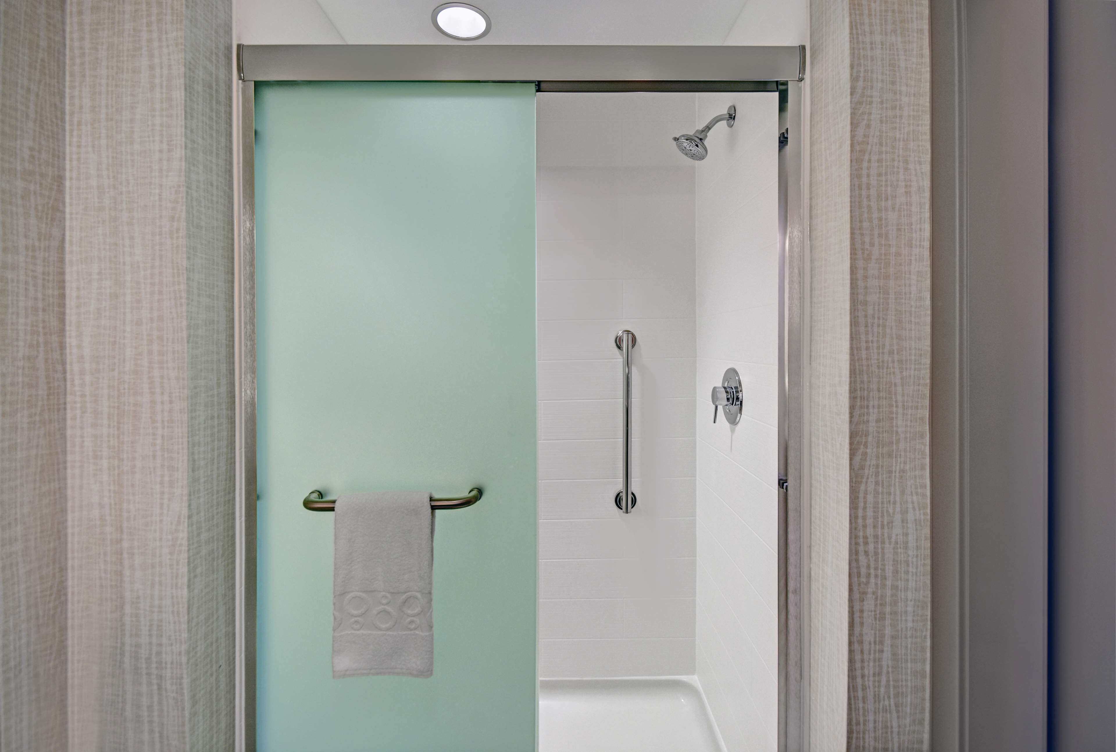 A bathroom with a glass door, a towel rack, a shower, and a bathtub.