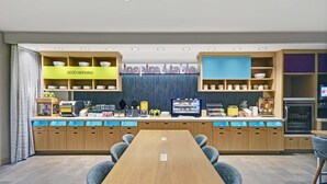 A modern kitchen with a long wooden table and chairs, equipped with various appliances and a display case.