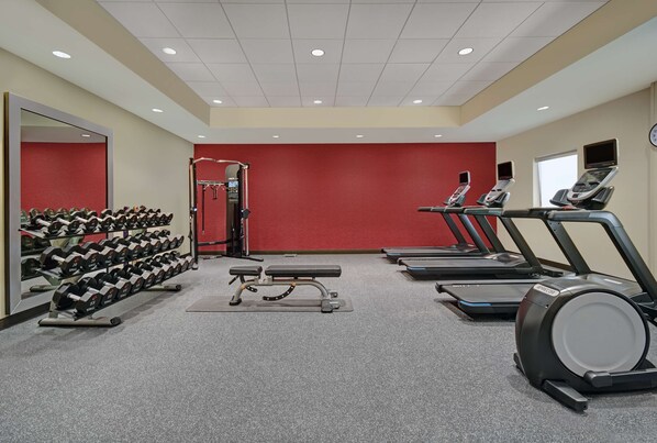 Une salle de sport équipée de tapis de course, d’haltères et d’appareils de musculation.