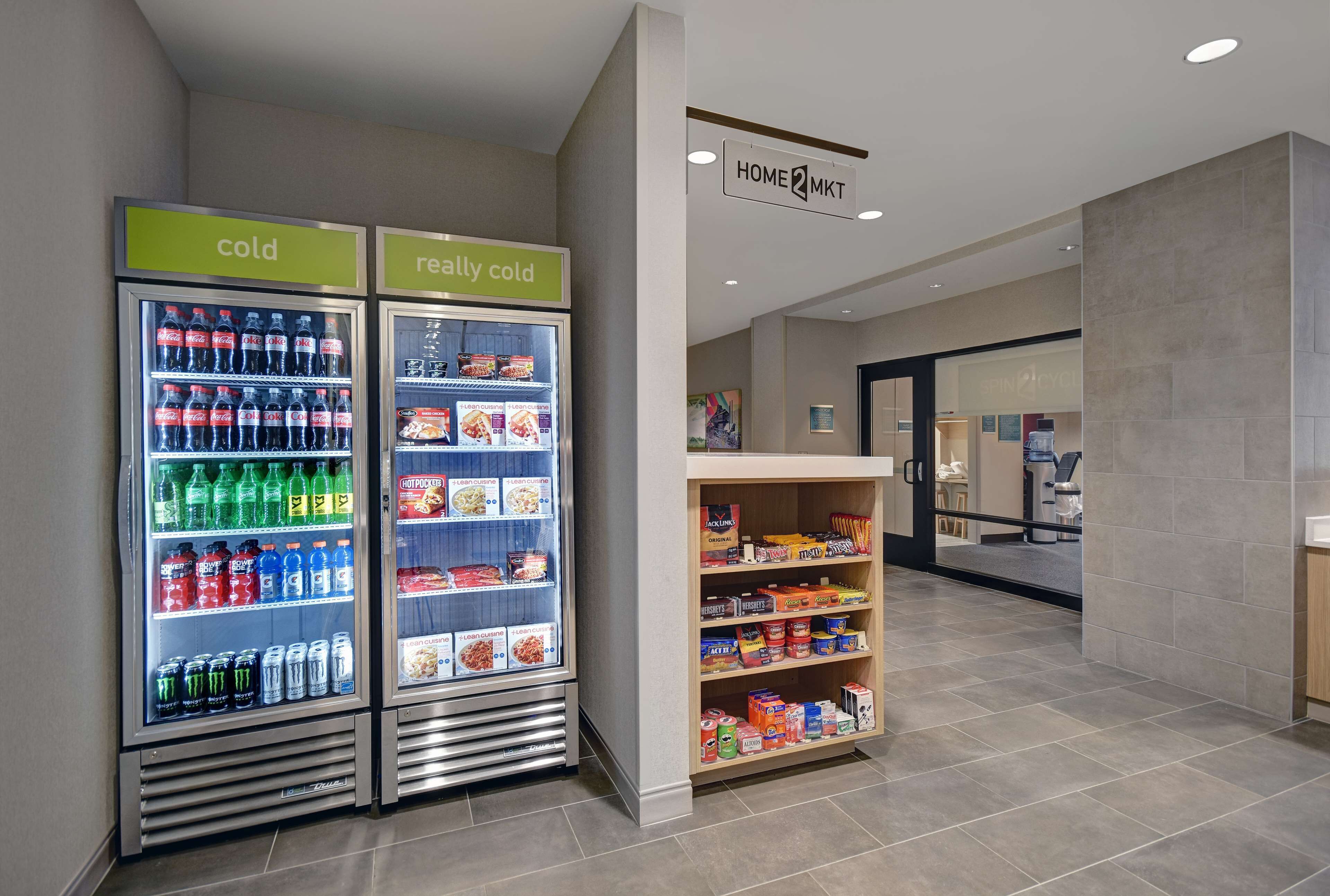 A hotel lobby with two beverage dispensers labeled "cold" and "really cold," and a snack shelf stocked with various items.