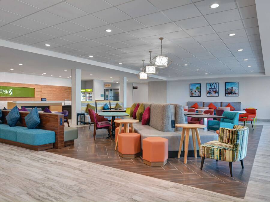 A modern hotel lobby with a reception desk, seating areas, and a dining space.