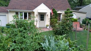 A house with a front porch, a flag, and a well-maintained garden. - Cozzy Get Away Priv. Apt/ St BarnabaS Hosp/NYC/EWR (Livingston)