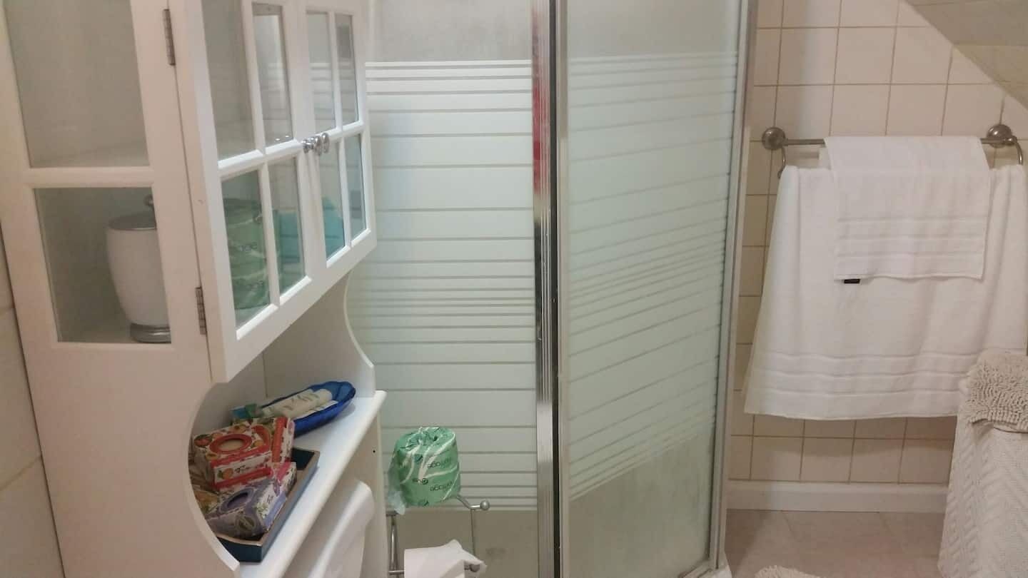 Une salle de bain avec une douche à parois de verre, un porte-serviettes blanc et un meuble contenant des articles de toilette.