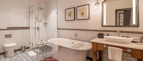 A bathroom with a freestanding bathtub, a toilet, a sink, and a shower. There are framed botanical prints on the wall and a large mirror above the sink.