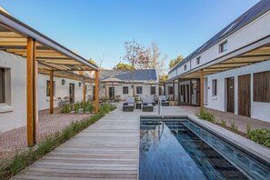 A modern outdoor pool area with a wooden deck, lounge chairs, and a clear blue pool. - Southern Sun de Wagen (Stellenbosch)