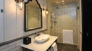 Un baño con un lavamanos blanco, un espejo grande y una ducha con puerta de cristal.
