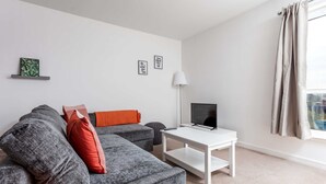 Ein modernes Wohnzimmer mit grauem Sofa, einem weißen Couchtisch und einem Flachbildfernseher.