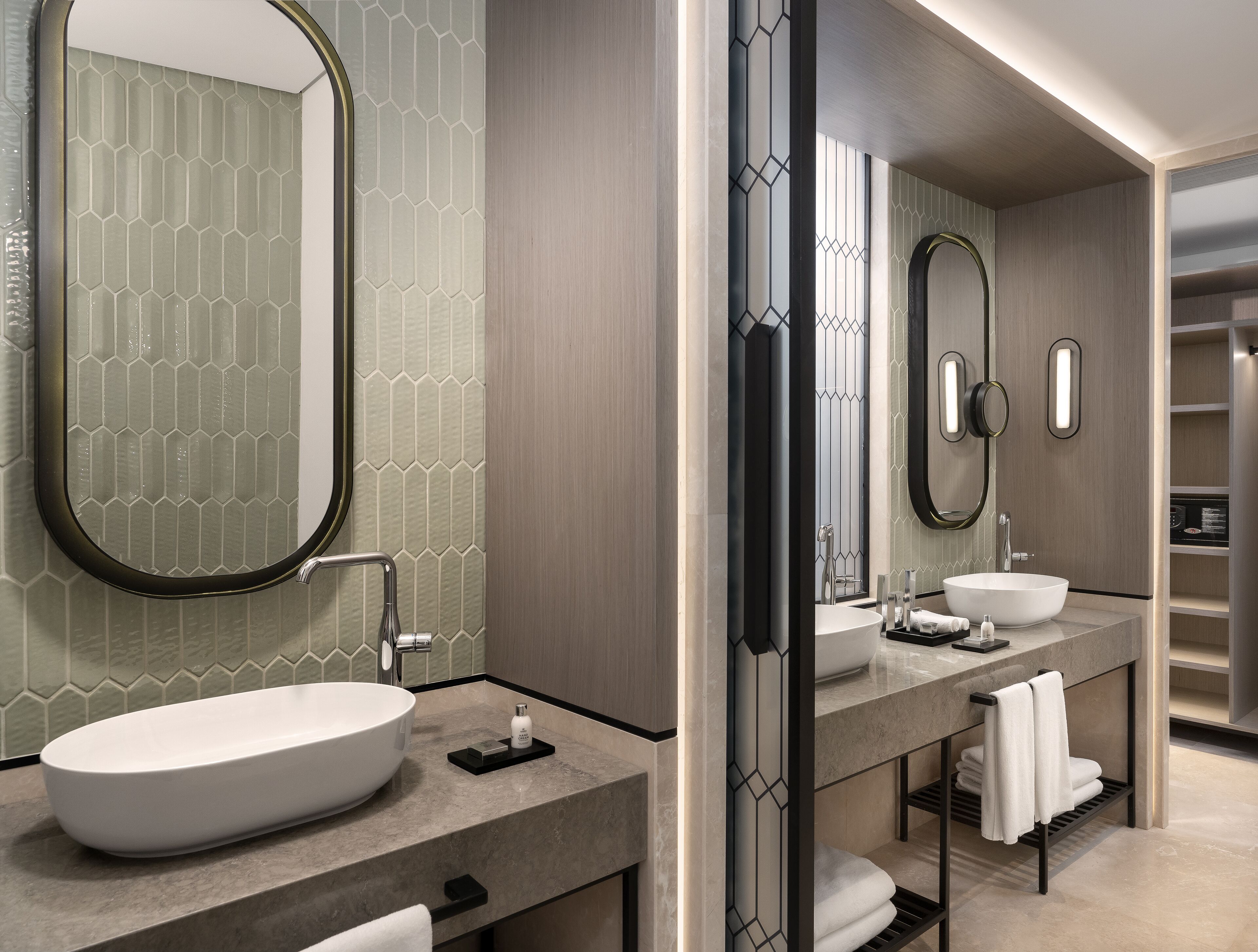 A modern bathroom with a large oval sink, two mirrors, and a vanity with a towel rack.